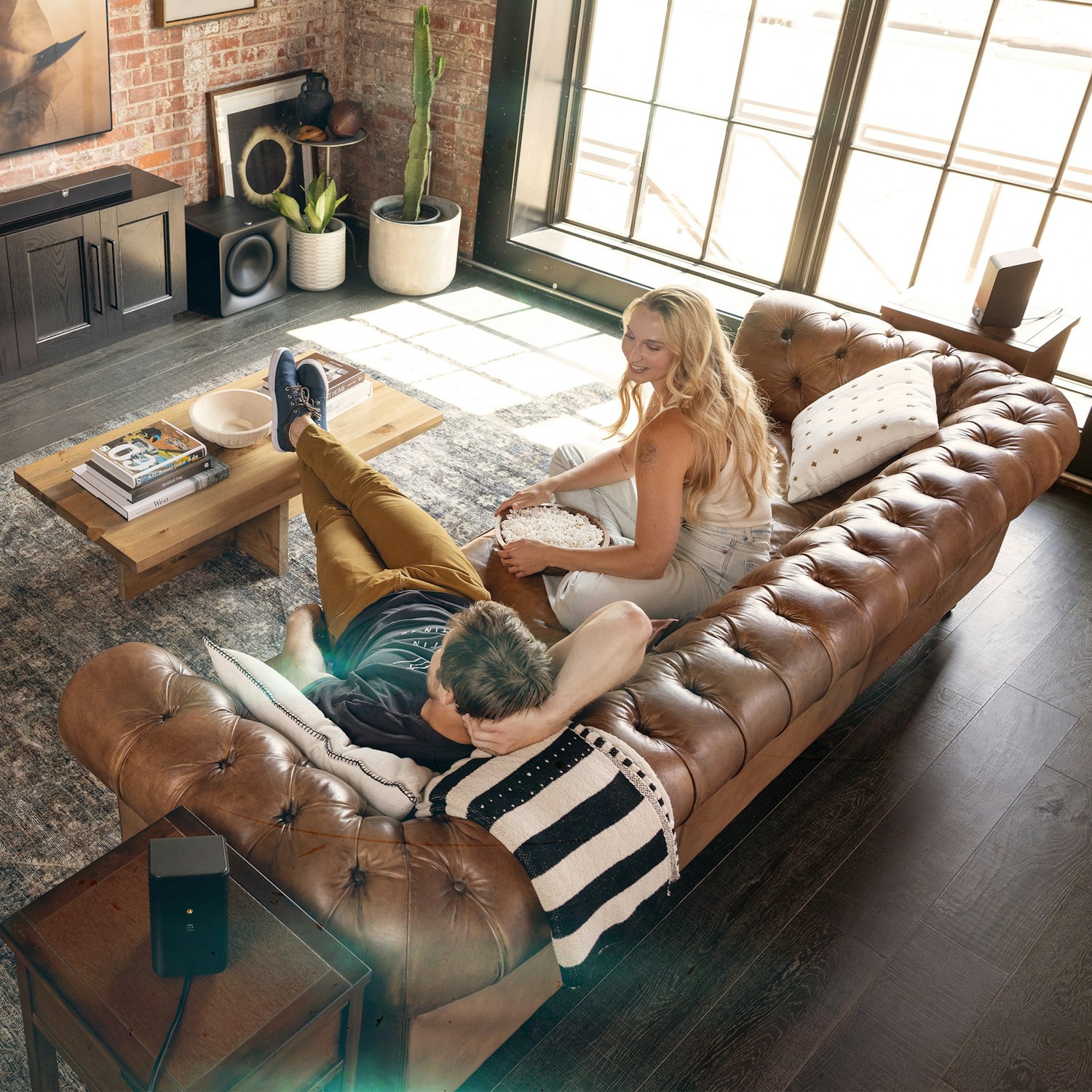 Klipsch Flexus CORE 300 BK and SURR 200 and two SUB 200 in living room with couple watching tv on leather couch v02 2000x2000