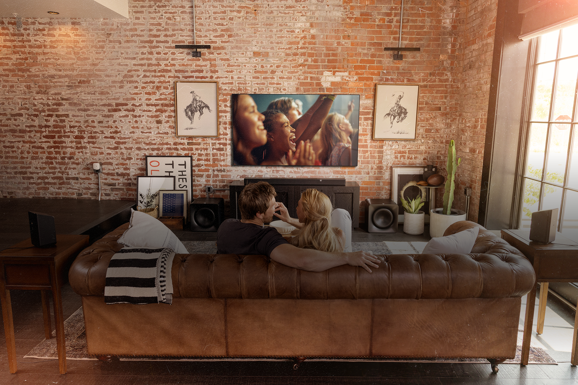 Klipsch Flexus CORE 300 BK and SURR 200 and two SUB 200 in living room with couple watching tv on leather couch 2000x1333