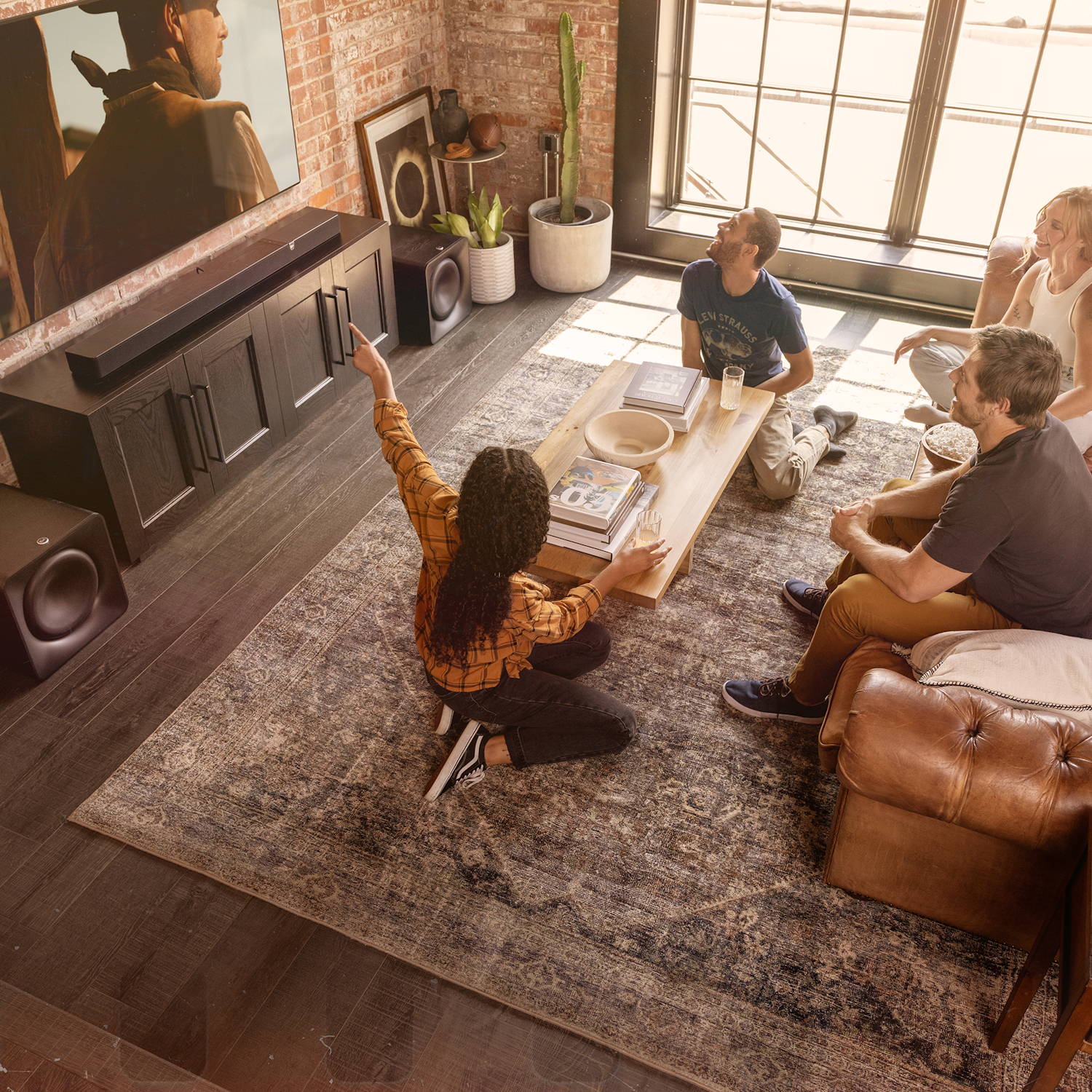 Klipsch Flexus CORE 300 BK and two SUB 200 in living room with group of friends interacting in front of tv 2000x2000